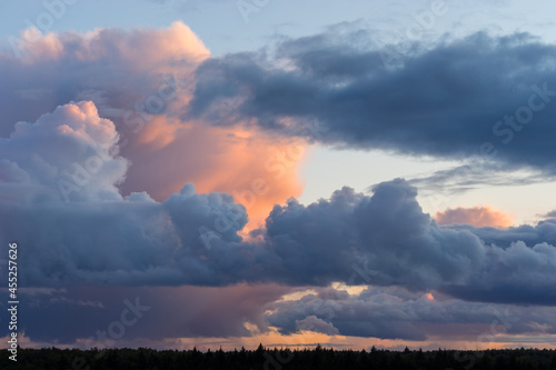 Beautiful colored dramatic stormy cumulus clouds on sky at sunset over forest horizon © evgenydrablenkov