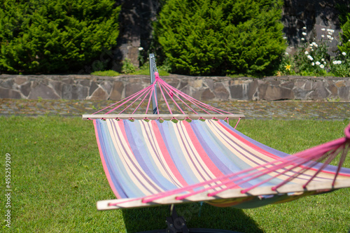 Colored hammock in the backyard. Empty hammock. Backyard multi colored fabric hammock with stand