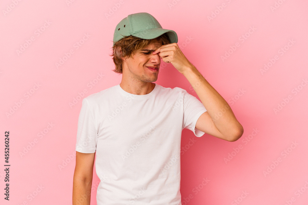Young caucasian man with make up isolated on pink background having a head ache, touching front of the face.