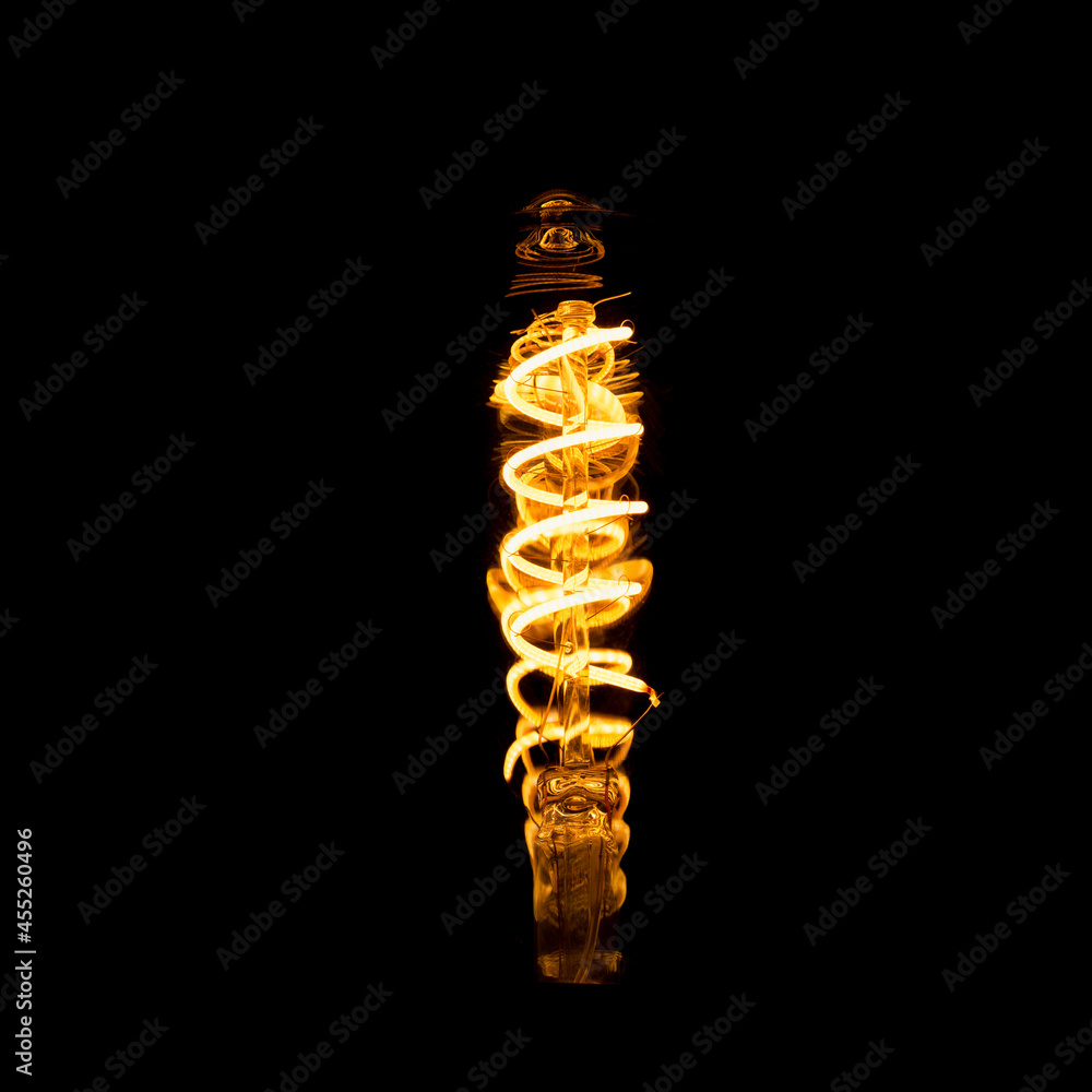 Obraz premium Edison's light bulb with incandescent tungsten filament, low expose in dark room. light picture for overlay or screen concepts. 