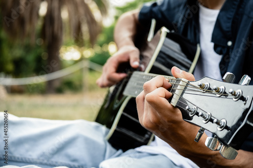 Caucasian man playing the guitar in the park. Close up.