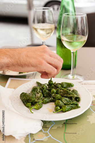 Vertical shot of Spanish vegetarian tapas of pimientos de padrón with two glasses of white wine from Galicia community. 