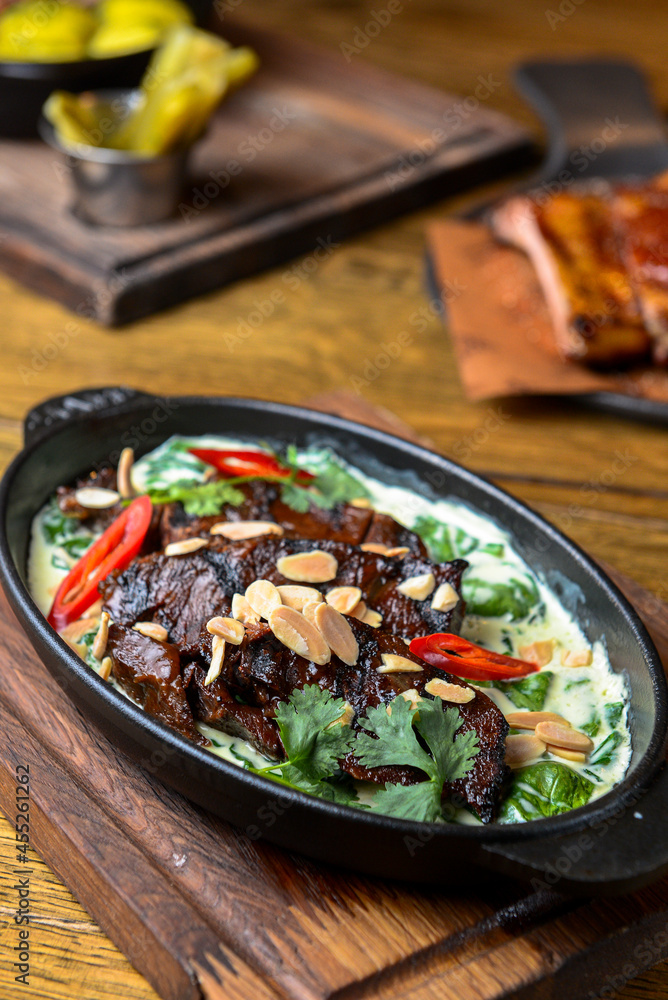 Meat with vegetables served with sauce in a pot over rustic wooden background. Rustic style dinner Meat with vegetables served with sauce in a pot over rustic wooden background. Rustic style dinner