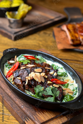 Meat with vegetables served with sauce in a pot over rustic wooden background. Rustic style dinner