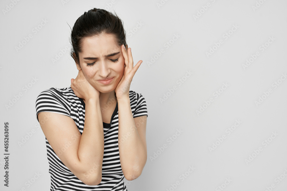 brunette in a striped t-shirt holding her head health problems brunette in a striped t-shirt holding her head health problems
