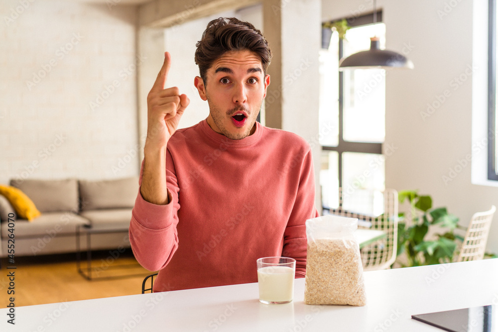 Young mixed race man eating oatmeal and milk for breakfast in his kitchen having an idea, inspiration concept. Young mixed race man eating oatmeal and milk for breakfast in his kitchen having an idea, inspiration concept.