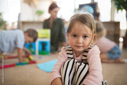 Portrait of small nursery school girl indoors in classroom, looking at camera.