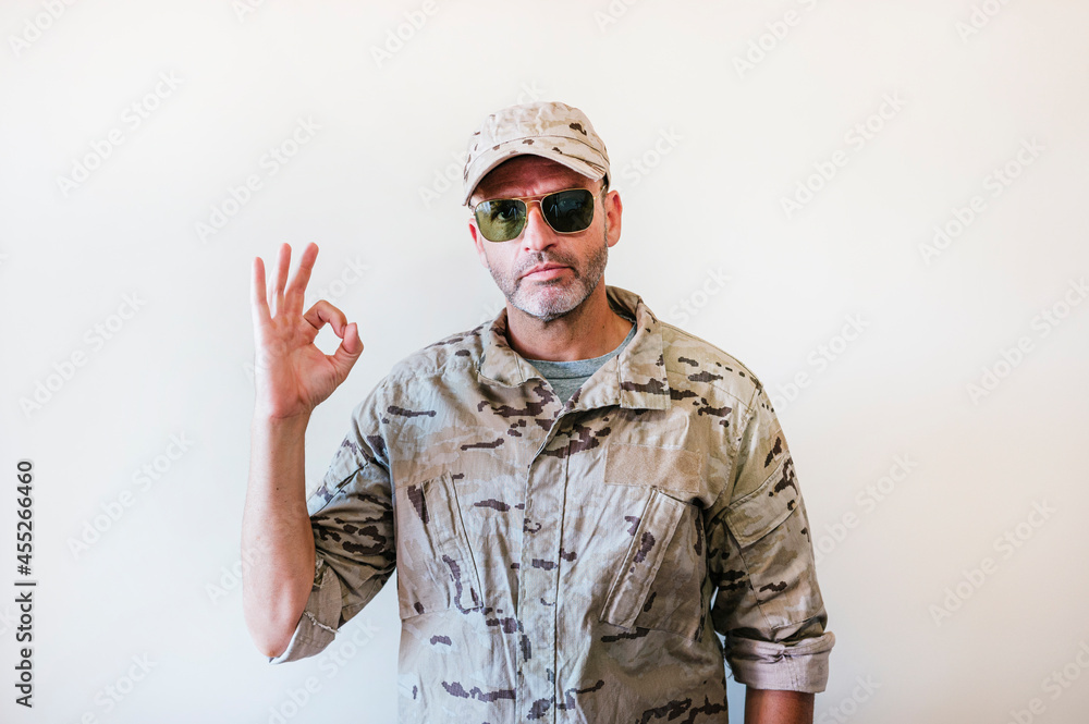 Caucasian man in camouflaged military uniform making OK gesture, positivity concept. Caucasian man in camouflaged military uniform making OK gesture, positivity concept.