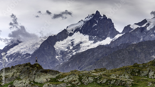 Paysage de montagne présentant un jeune garçon sur un rocher devant un sommet enneigé