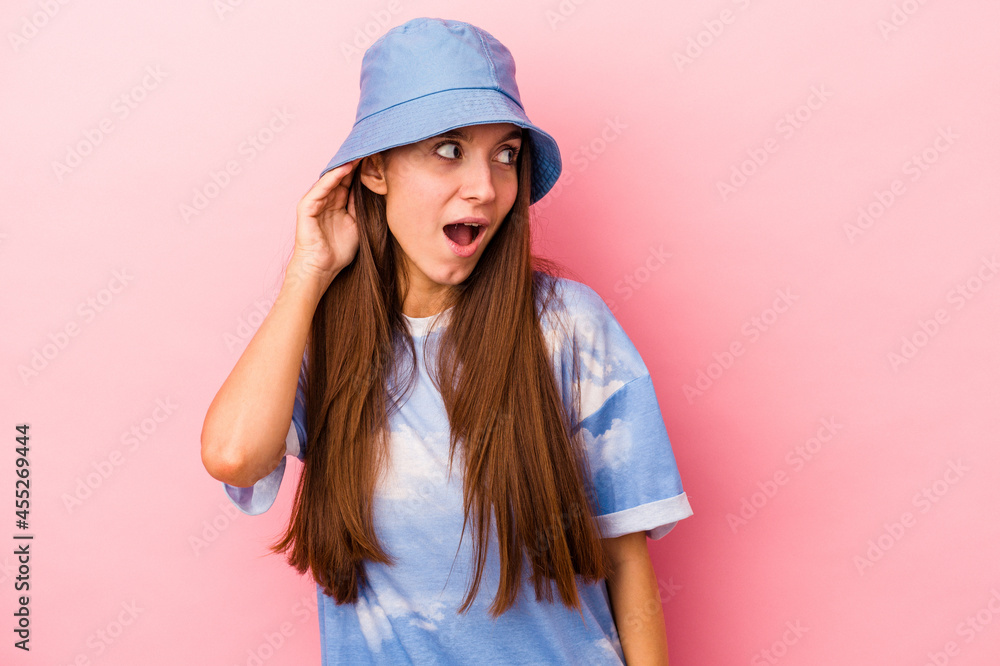 Young caucasian woman isolated on pink background trying to listening a gossip. Young caucasian woman isolated on pink background trying to listening a gossip.