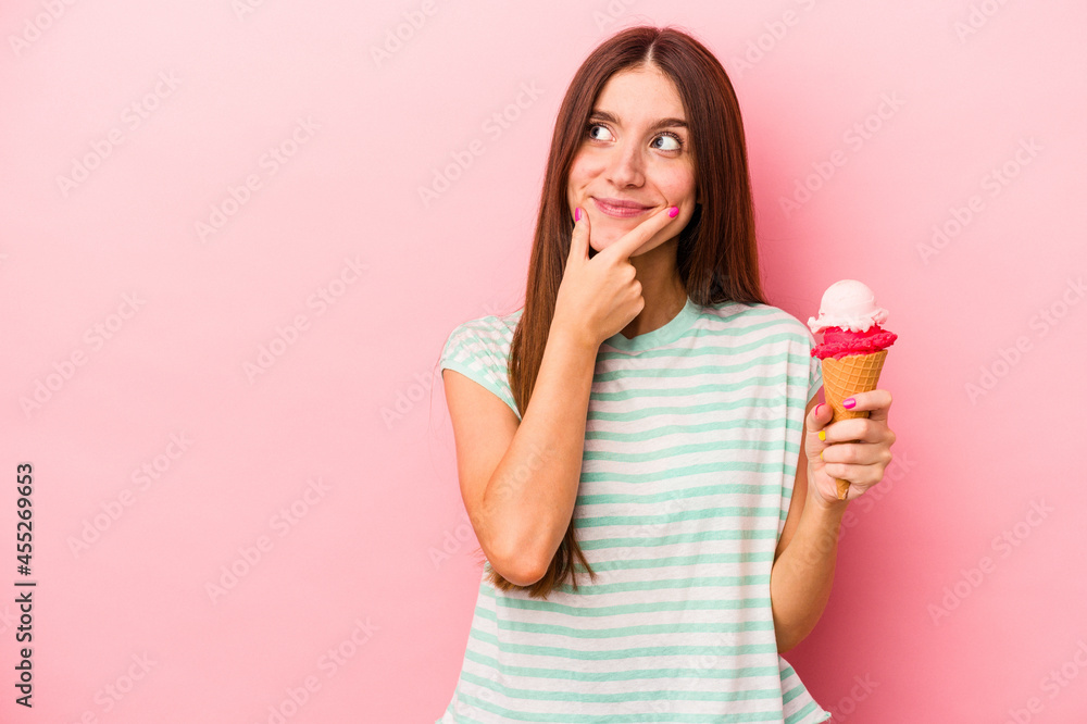 Young caucasian woman holding an ice cream isolated on pink background looking sideways with doubtful and skeptical expression. Young caucasian woman holding an ice cream isolated on pink background looking sideways with doubtful and skeptical expression.