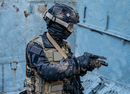 modern soldier in black multicam uniform with rifle, urban background 