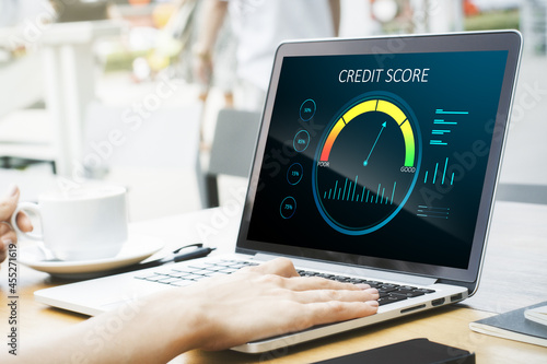 Close up of hands at wooden desktop with laptop computer, coffee cup and abstract credit score scale on screen. Finance and consumer concept. photo