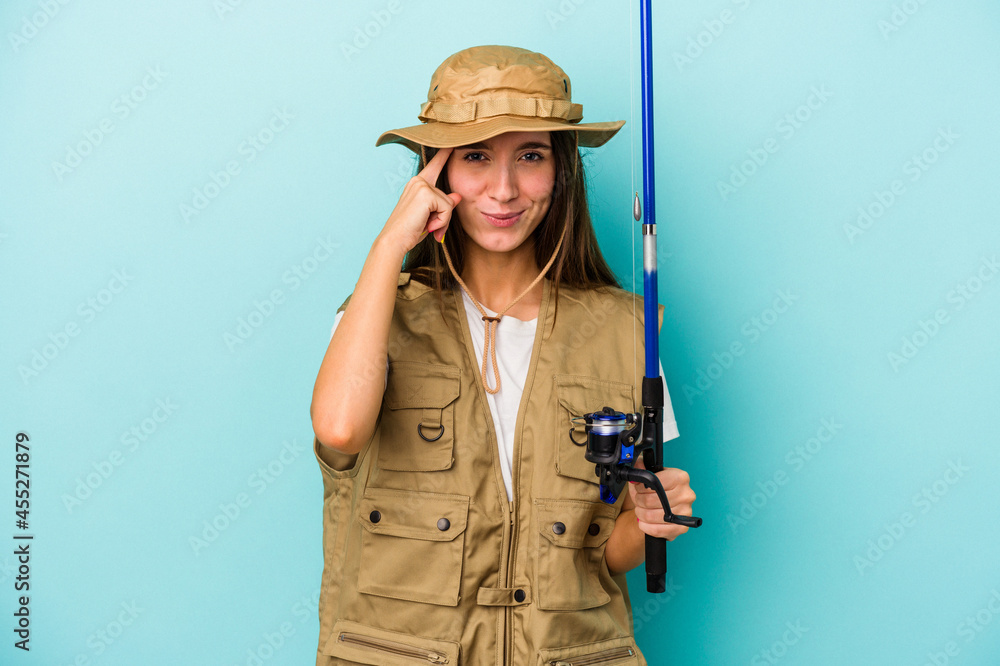 Young caucasian fisherwoman isolated on blue background pointing temple with finger, thinking, focused on a task. Young caucasian fisherwoman isolated on blue background pointing temple with finger, thinking, focused on a task.