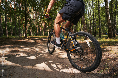 Muscular young male riding bike in forest