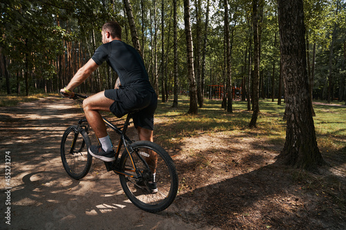 Athletic young man going cycling in forest