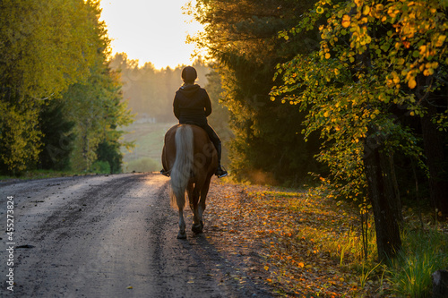 Woman horseback riding on country road at sunset © citikka