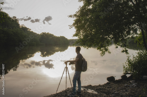 Hispanic man taking photos of a calm lake during sunset in Yurumi Valley at Matanzas, Cuba photo