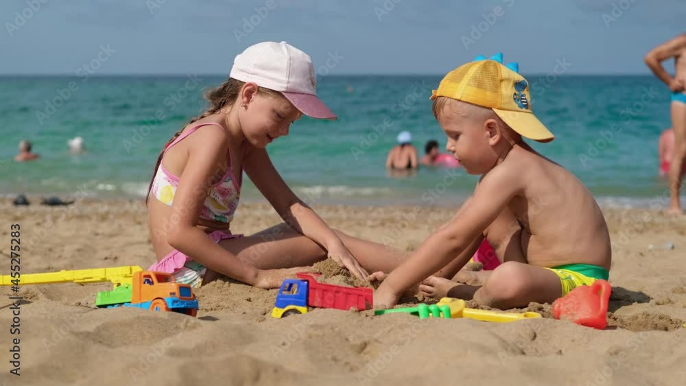 Children are playing on the beach. Summer water fun for the whole family. Boy and girl play with sand on the seashore. Children are playing on the beach. Summer water fun for the whole family. Boy and girl play with sand on the seashore.