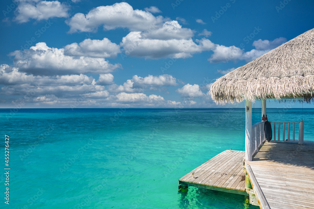 Water villas in the ocean. Seascape, sunny blue cloudy sky. Idyllic luxury travel background, bungalow. Maldives or French Polynesia tropical paradise banner concept