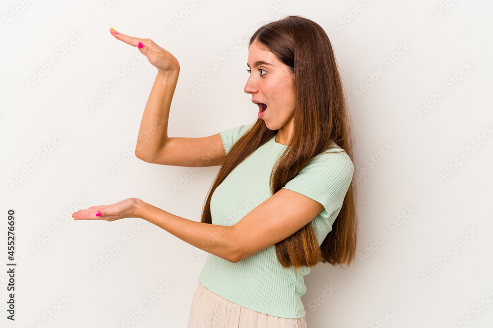 Young caucasian woman isolated on white background shocked and amazed holding a copy space between hands. Young caucasian woman isolated on white background shocked and amazed holding a copy space between hands.