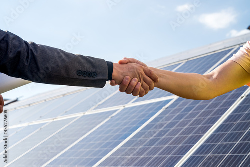 shaking hands against solar panel  after the conclusion of the agreement in the renewable energy