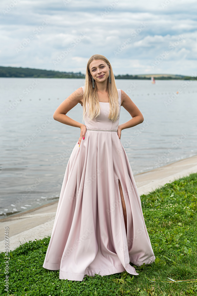 Young woman enjoying summer time posing alone in cute ping dress near lake Young woman enjoying summer time posing alone in cute ping dress near lake