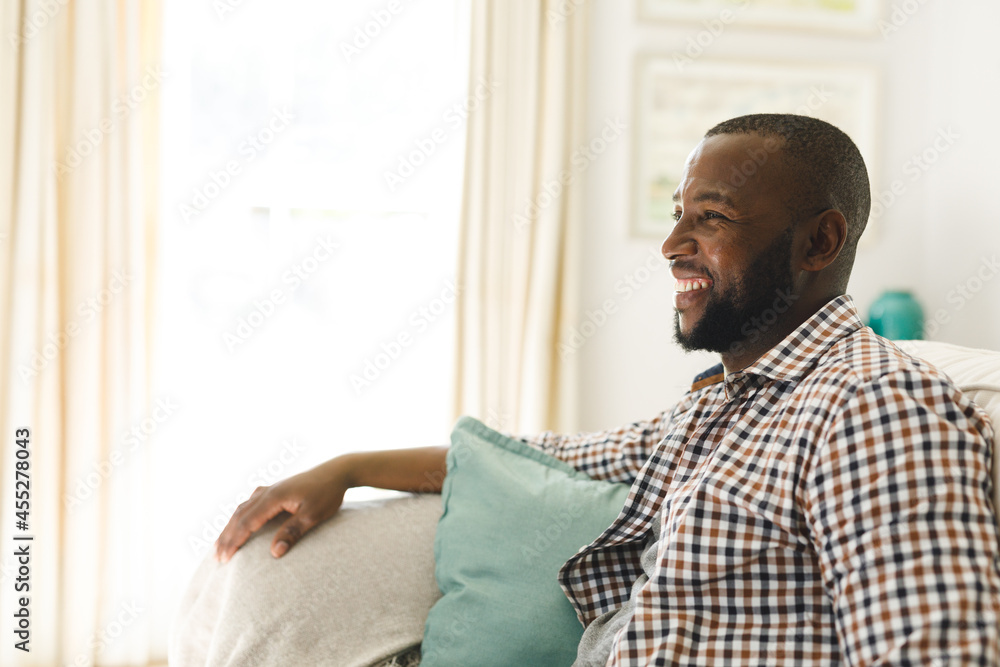 African american man smiling and sitting on couch in living room African american man smiling and sitting on couch in living room