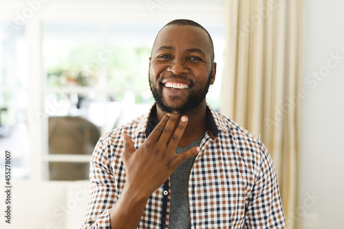 Portrait of african american man smiling and looking at camera in living room talking sign language