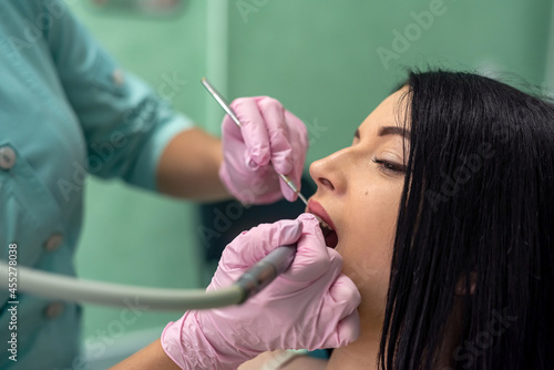 Fototapeta Naklejka Na Ścianę i Meble -  Dentist reviewing patient's teeth with mirror in  gloves