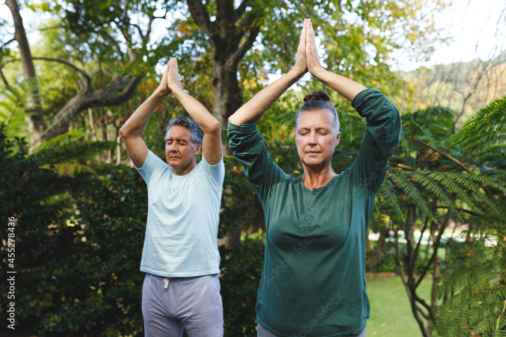 Happy senior caucasian couple practicing yoga, meditating in sunny garden Happy senior caucasian couple practicing yoga, meditating in sunny garden