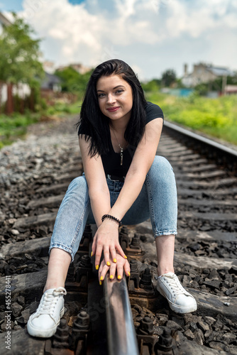 happy woman sitting on railroad in summer cloth, railway tracks