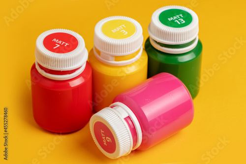 Color oil paint bottles on yellow background