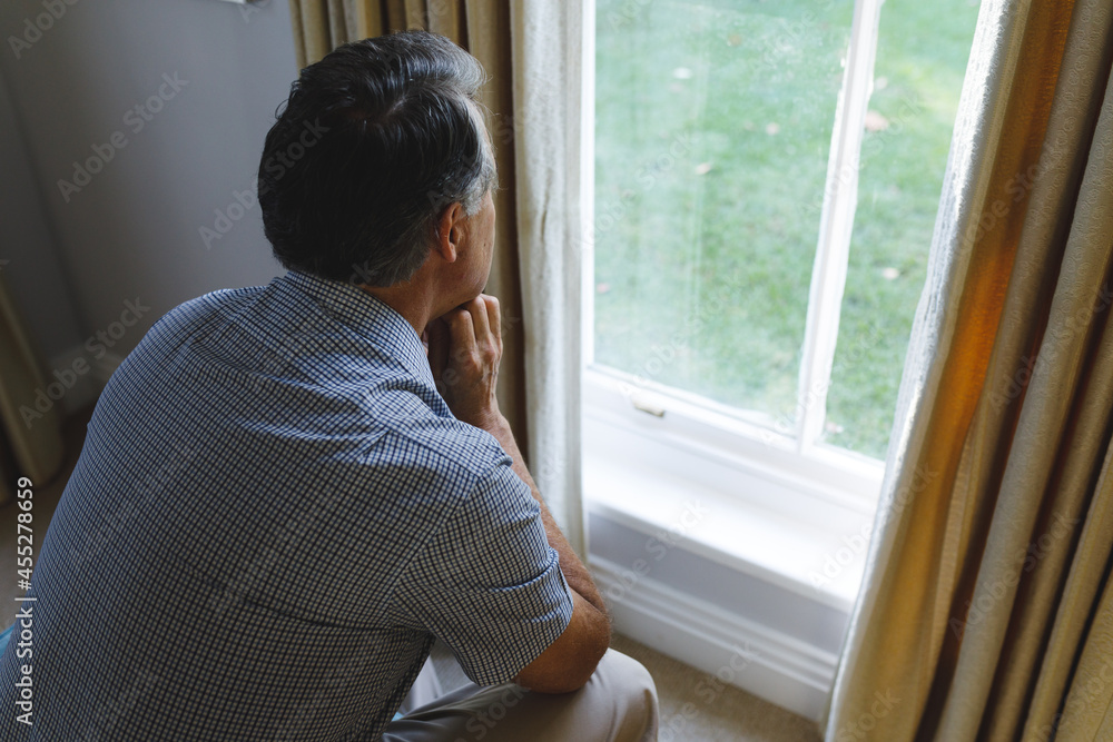 Thoughtful senior caucasian man sitting on sofa and looking through window Thoughtful senior caucasian man sitting on sofa and looking through window