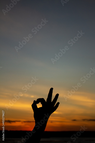 Silhouette of a man's hand during sunset making the OK symbol.