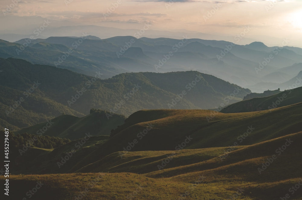 Beautiful panorama of green hills and mountains at sunset.