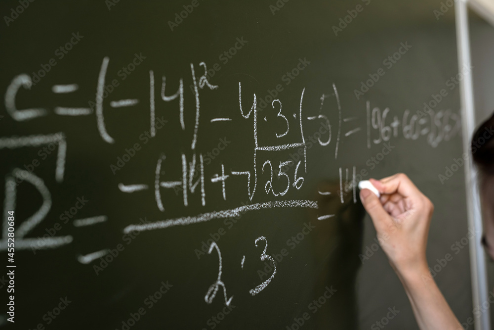 female hand writing math formulas on the classboard female hand writing math formulas on the classboard