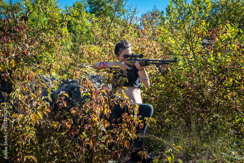 female hunter in top using weapon or rifle at nature