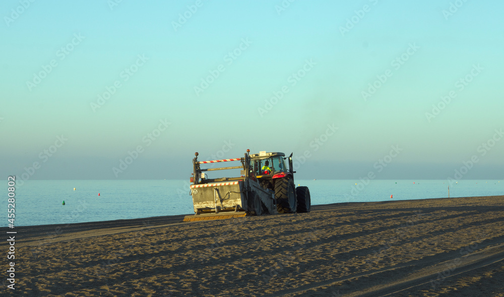 Fototapeta premium A tractor moving the sand on the beach