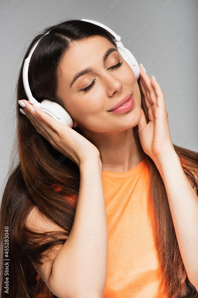 Fototapeta premium smiling woman in wireless headphones listening music isolated on grey