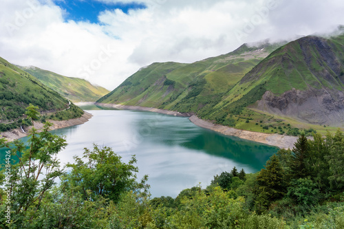 Beautiful summer panorama of the mountain lake in Vaujany, France. Cloudy  view in the French Alps, Europe. Scenery landscape of high plateau.
