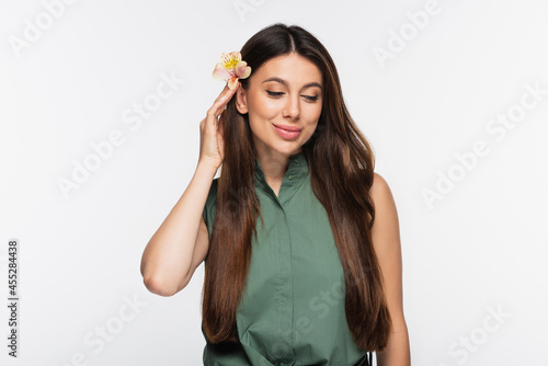 smiling woman with flower in shiny long hair isolated on grey