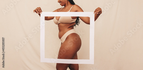 Foto Happy young woman holding a picture frame in front of her body