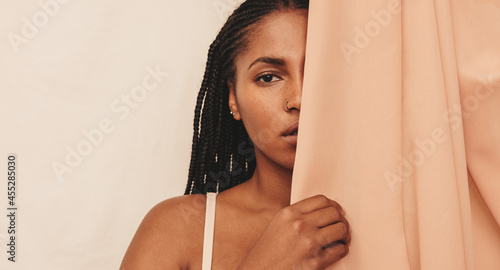 Young woman standing behind a studio curtain