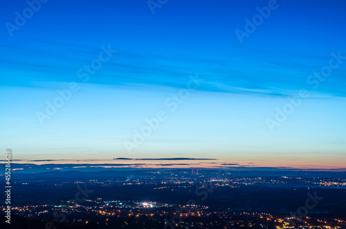 Looking across a mixture of the countryside and towns scattered with street lights just before sunrise. Looking down from the Malvern Hills, Worcestershire, UK.