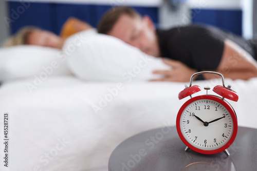 Man and woman sleep in bedroom on alarm clock at ten in morning