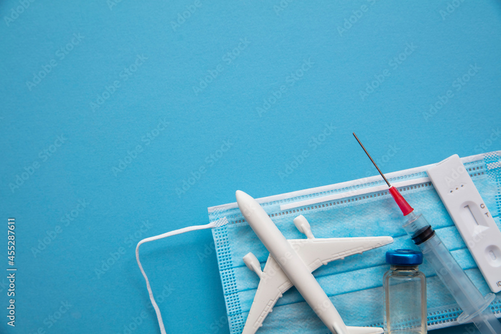 Covid air travel background. Airplane with a coronavirus protective face mask vaccine needle and test. - obrazy, fototapety, plakaty 