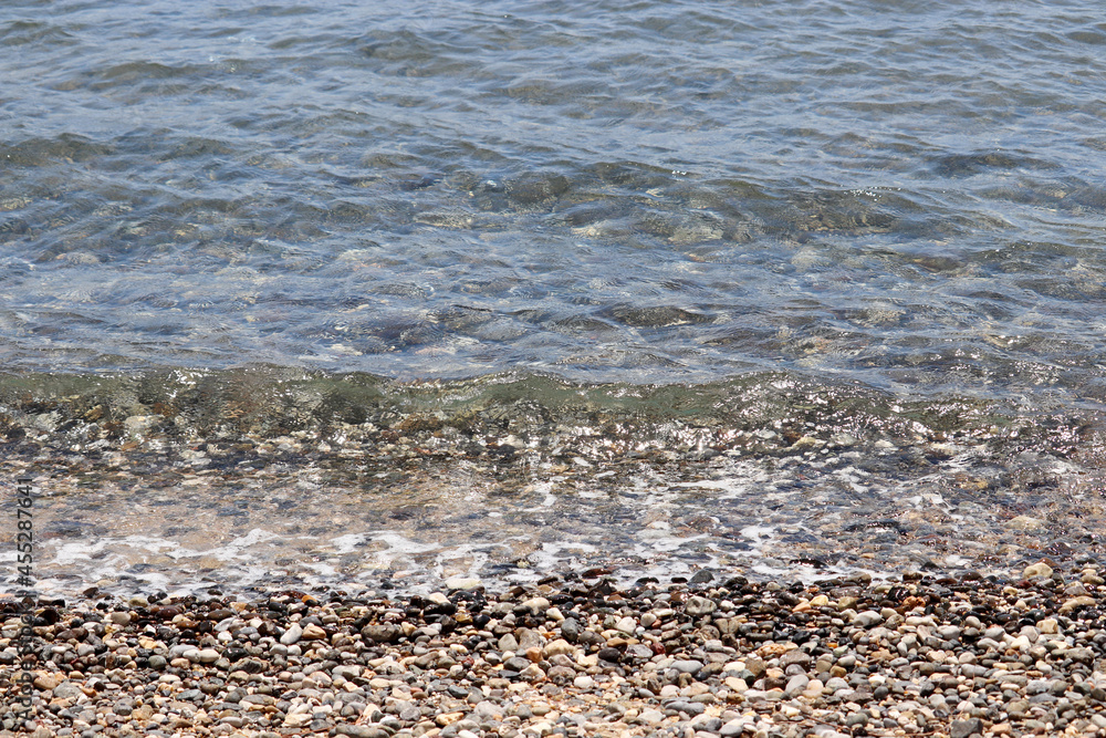 Wet pebble stones on background of sea waves. Beach vacation, travel concept Wet pebble stones on background of sea waves. Beach vacation, travel concept