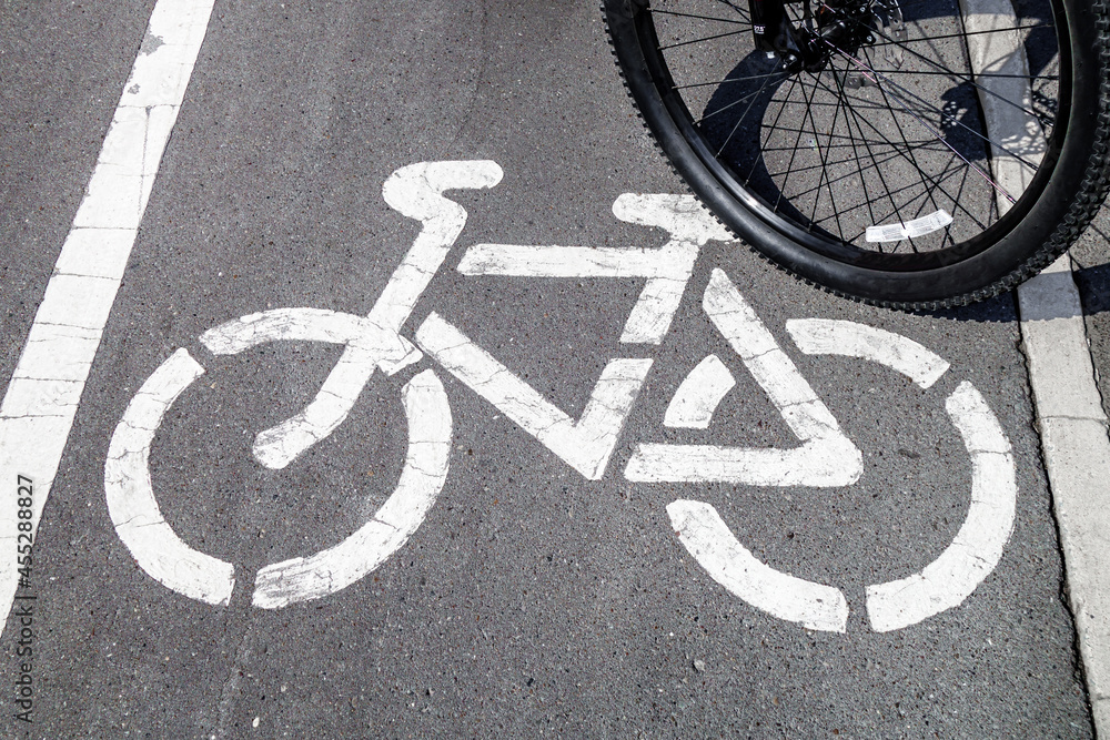 Bicycle symbol on designated track. There is cyclist little to side, wheel is visible