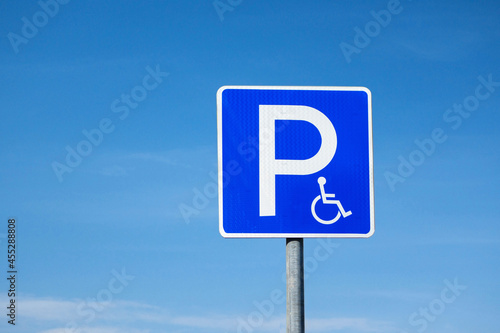 Disabled parking international road sign. Blue sky on background